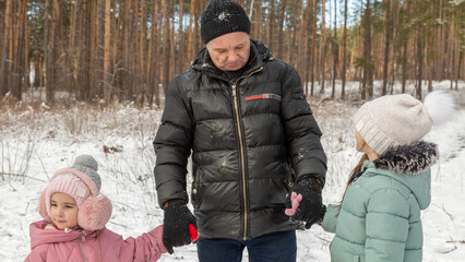 Little girls with her grandfather walk in a snowy forest, have fun together