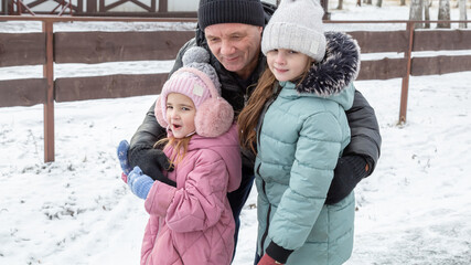 Little girls with her grandfather walking in park on snowy winter day