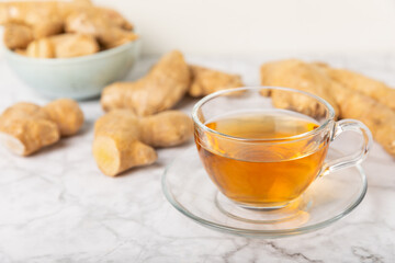 Cup of hot ginger tea with slices of ginger root on wooden background. Warming drink. Alternative medicine. Tea with honey, lemon, ginger and mint. Space for text. Copy space
