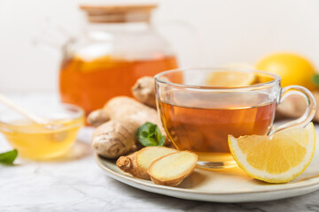 Cup of hot ginger tea with slices of ginger root on wooden background. Warming drink. Alternative medicine. Tea with honey, lemon, ginger and mint. Space for text. Copy space