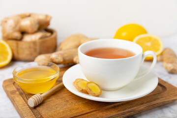 Cup of hot ginger tea with slices of ginger root on wooden background. Warming drink. Alternative medicine. Tea with honey, lemon, ginger and mint. Space for text. Copy space
