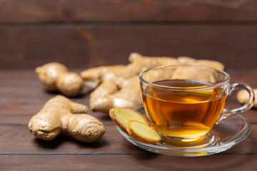 Cup of hot ginger tea with slices of ginger root on wooden background. Warming drink. Alternative medicine. Tea with honey, lemon, ginger and mint. Space for text. Copy space