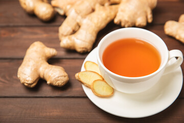 Cup of hot ginger tea with slices of ginger root on wooden background. Warming drink. Alternative medicine. Tea with honey, lemon, ginger and mint. Space for text. Copy space