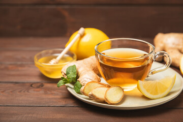 Cup of hot ginger tea with slices of ginger root on wooden background. Warming drink. Alternative medicine. Tea with honey, lemon, ginger and mint. Space for text. Copy space