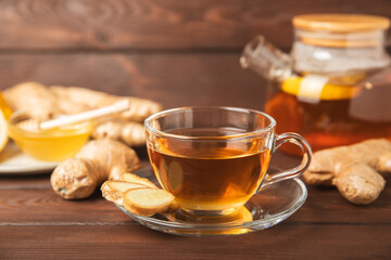 Cup of hot ginger tea with slices of ginger root on wooden background. Warming drink. Alternative medicine. Tea with honey, lemon, ginger and mint. Space for text. Copy space