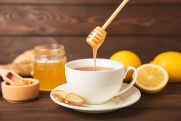 Cup of hot ginger tea with slices of ginger root on wooden background. Warming drink. Alternative medicine. Tea with honey, lemon, ginger and mint. Space for text. Copy space