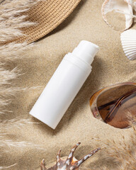 White one pump bottle, sunglasses, pampas grass and seashells on sand, Sunscreen cosmetic mockup