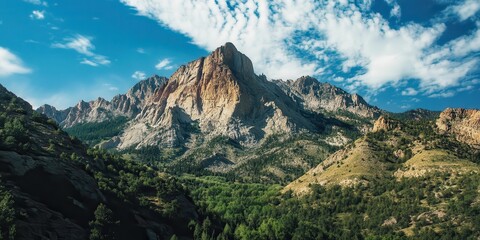Majestic mountain range under a vibrant blue sky with scattered clouds.