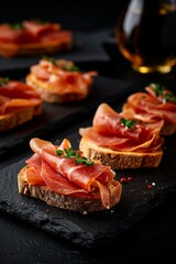 Pan con Tomate: Rustic bread slices brushed with ripe tomato, olive oil, and a pinch of salt, served with thin slices of Serrano ham on the side.