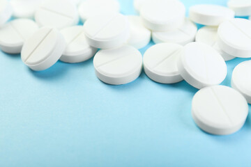 Many antibiotic pills on light blue background, closeup. Space for text