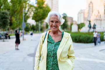 Fototapeta premium Smiling senior woman enjoying a walk in a city park