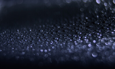 Macro view of glittering water drops creating an abstract effect on a dark surface in low light conditions