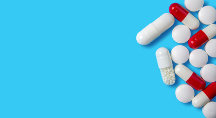 Variety of colorful capsules and tablets arranged on a blue background in a health-related setting
