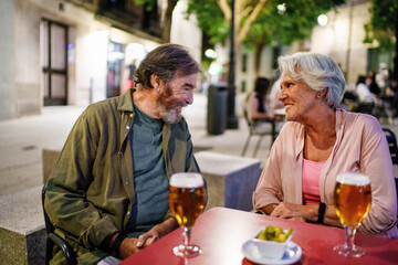 Happy senior couple enjoying beer and tapas at outdoor cafe