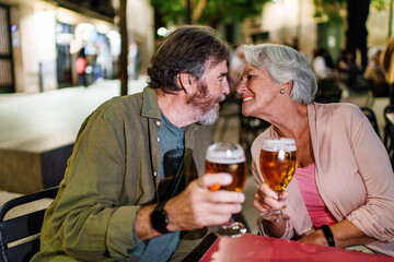 Happy senior couple drinking beer at outdoor pub