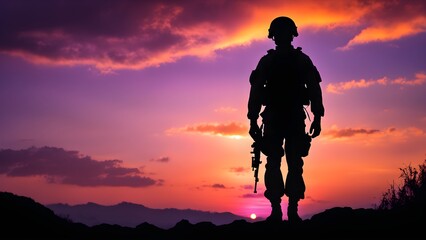 Fototapeta premium Silhouette of a soldier standing on a mountaintop at sunset, holding a rifle.