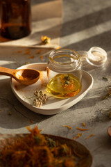 Side view of different wild herbal medicinal plants, oils, turmeric powder, gathered on a table in a process of preparation calendula, yarrow