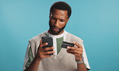 Confused, phone and black man with credit card in studio for online shopping, digital purchase or...