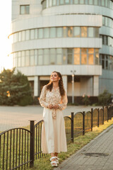 Obraz premium Portrait of a beautiful woman dressed in stylish casual clothes posing on the street. A successful woman in a big city who leads an urban lifestyle. Background from office buildings