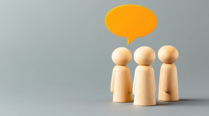 Wooden figures with yellow speech bubble on gray background