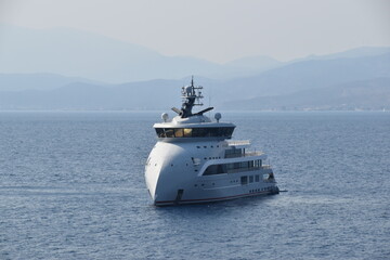 Obraz premium A white modern luxury yacht in a small port in the Mediterranean Sea, Greece