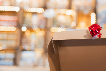 Wrapped gift with a red bow resting on a cardboard box in a softly lit store setting