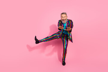 Smiling senior man in colorful striped suit posing energetically against pink background