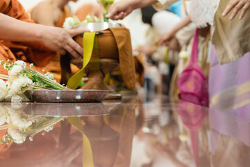 Traditional Thai Buddhist almsgiving ceremony with people offering food and flowers to monks in saffron robes.