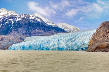 Distant view of Grey Glacier flowing into Lago Grey surrounded by mountains in Torres del Paine