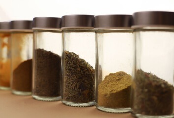 set of different spices in glass jars. paprika, pepper, turmeric, chili, dry basil and others