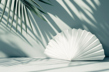 white paper fan and palm leaf shadows on a green background