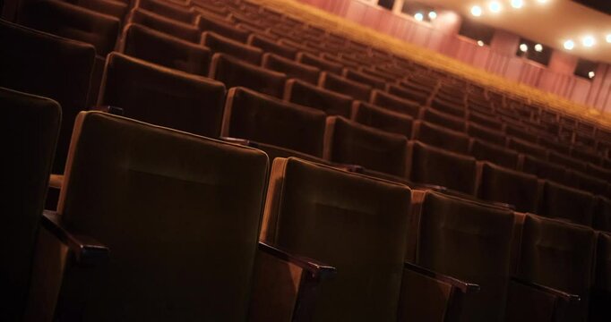 An atmospheric view of empty audience seats in a grand theater or concert hall. The warm lighting and elegant design of the interior evoke a sense of anticipation