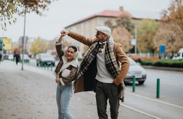 Obraz premium Happy couple embraces autumn as they walk down a city street, enjoying the crisp air and colorful scenery. Their cheerful expressions and stylish outfits capture the essence of urban outdoor leisure.
