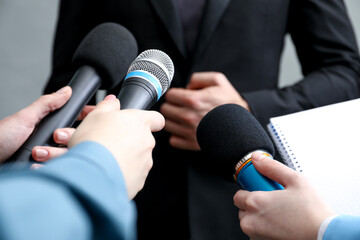 Group of journalists interviewing businesswoman on grey background, closeup