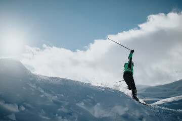 Skier in a green jacket navigating a snow-covered slope under a sunny, clear sky. Dramatic action and winter-adventure imagery highlight the exhilarating joy and energy associated with alpine skiing