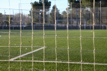 Corner of a soccer field where you can see the goal and the white lines of play on the green grass