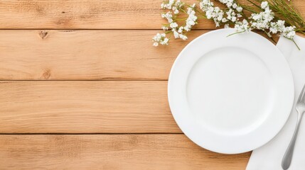 A white plate sits on a wooden table with a fork and a bunch of flowers