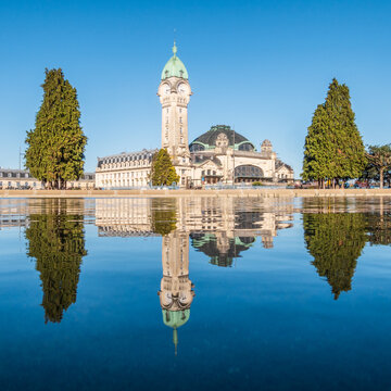 Square view of the train station in Limoges reflecting in blue water, France