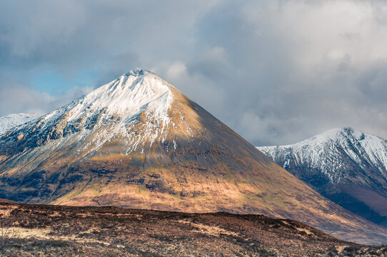 A dramatic landscape view of a snow-capped mountain range.  The image shows the rugged slopes of the mountains, with patches of snow clinging to the peaks and ridges.  - Powered by Adobe