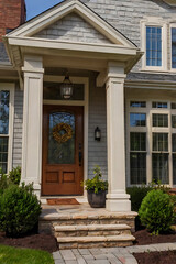 Elegant Home Exterior with Stone Porch and Columns. Beautiful Front Door and Landscaping. Perfect for Real Estate Listings and Architectural Inspiration.