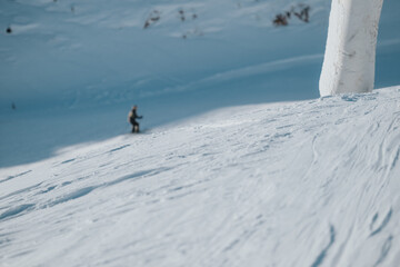 A snowboarder glides down a snowy slope on a sunny winter day, surrounded by breathtaking alpine...