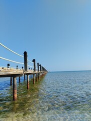  long pontoon bridge extending into the sea, open sea, sea coast, deserted beach without people, bridge on piles