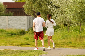 A young guy and his girlfriend are walking in the park along the lake shore. A walk of lovers in the fresh air on a day off. Family leisure in nature