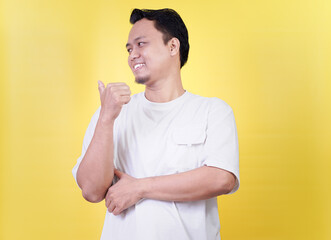 A smiling Asian man gives a thumbs up gesture towards the back against a bright yellow background