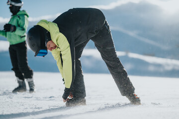 A skier wearing winter gear adjusts their equipment on a bright snowy mountain slope. The scene is...