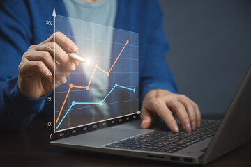 A person is analyzing graphs on a laptop, using virtual elements for interaction. Business finance background