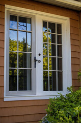 Charming Exterior French Door and Window Combination on a Brown House. The scene shows a beautiful view of nature through the glass panes