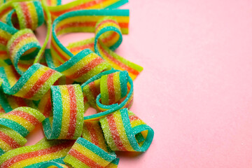 Tasty rainbow sour belts on pink background, closeup. Space for text