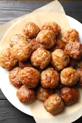 Many delicious meatballs on dark wooden table, top view
