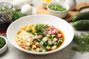 Delicious okroshka soup and ingredients on grey table, closeup